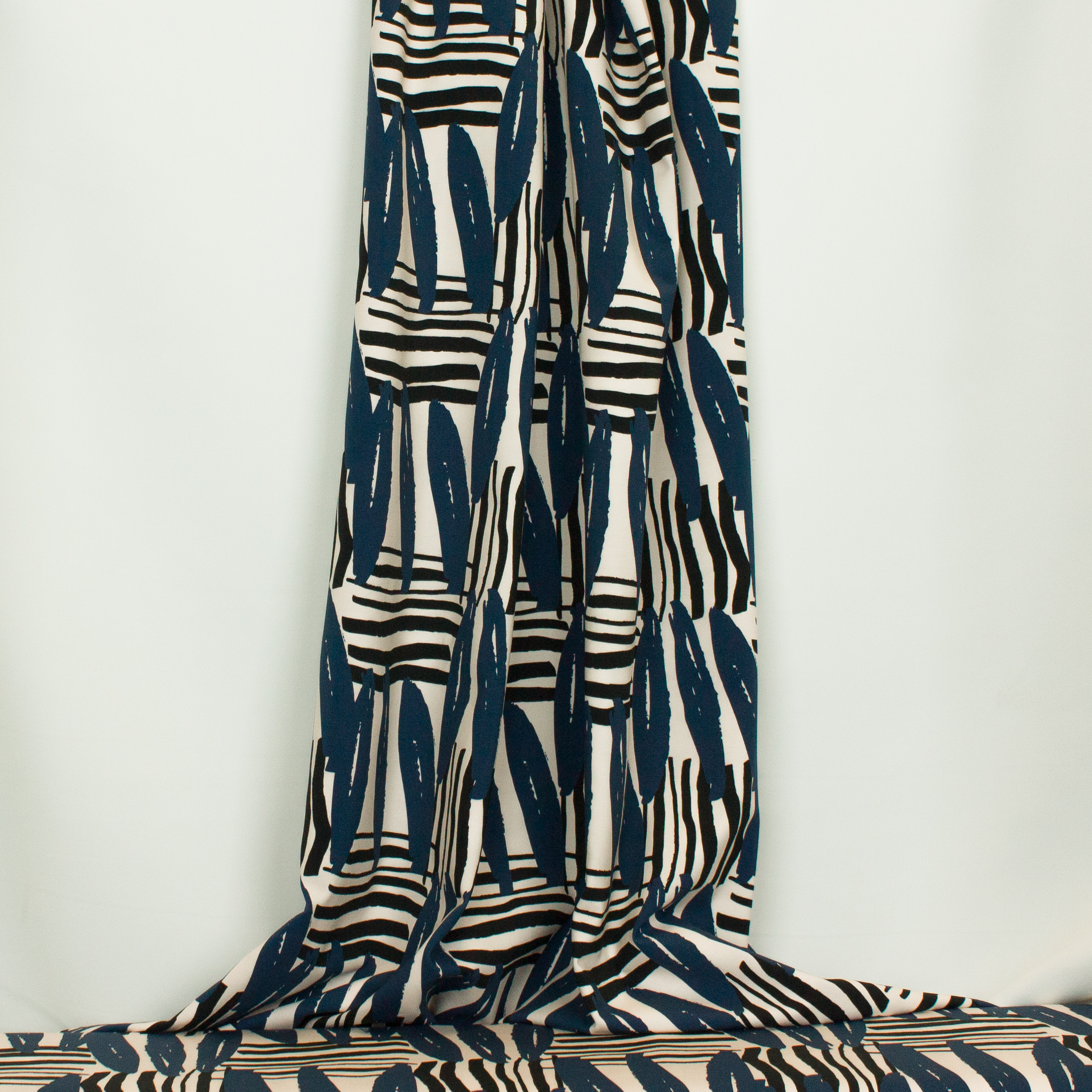 Ecru tricot met abstracte strepen in zwart en blauw