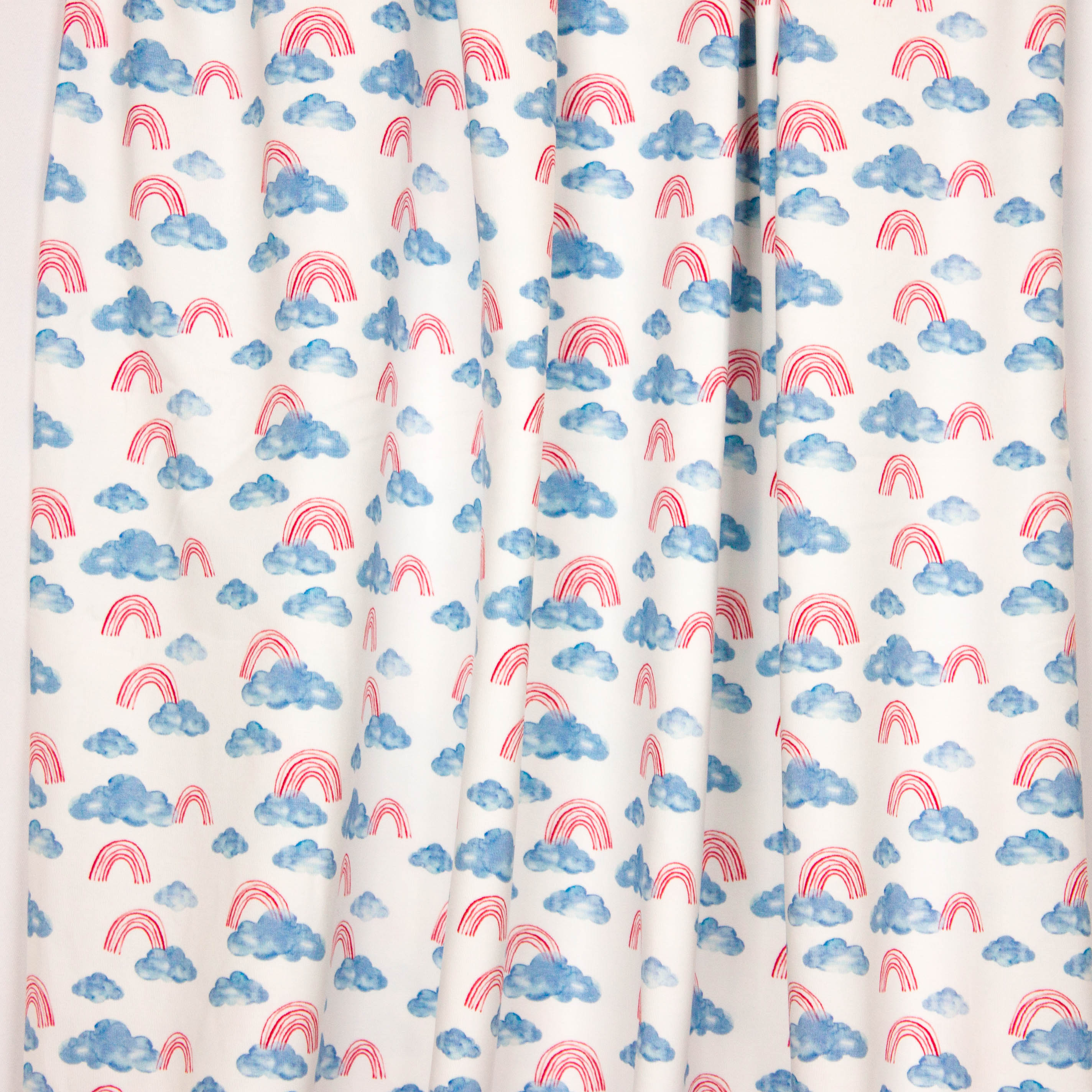 Witte tricot met blauwe wolken en rode regenbogen
